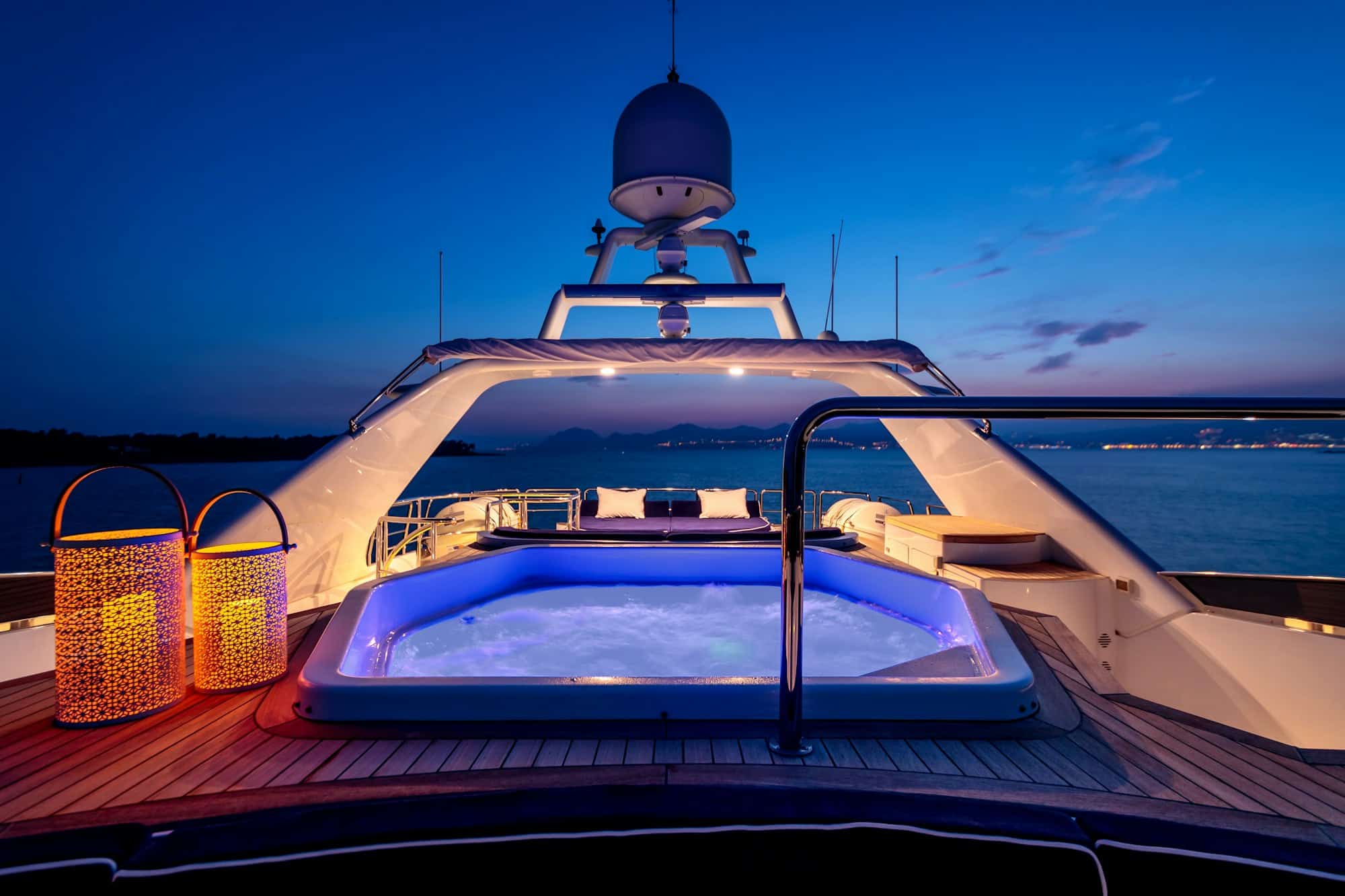 Luxury yacht with lights and a jacuzzi sailing in the sea at night